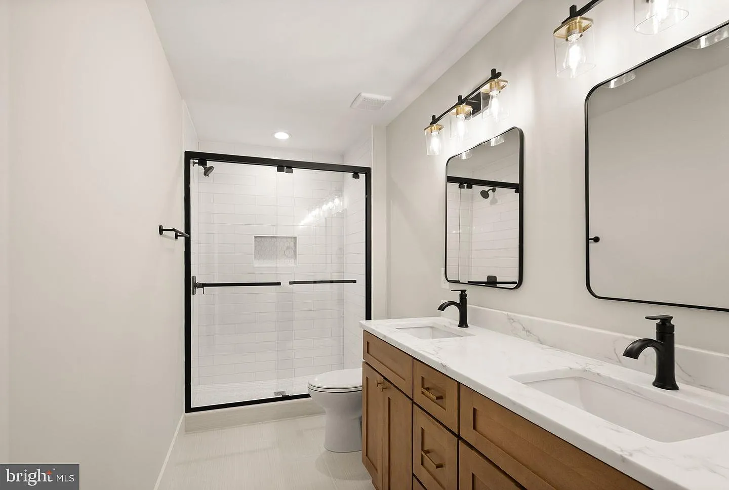 Primary bathroom with wood double vanity and glass shower