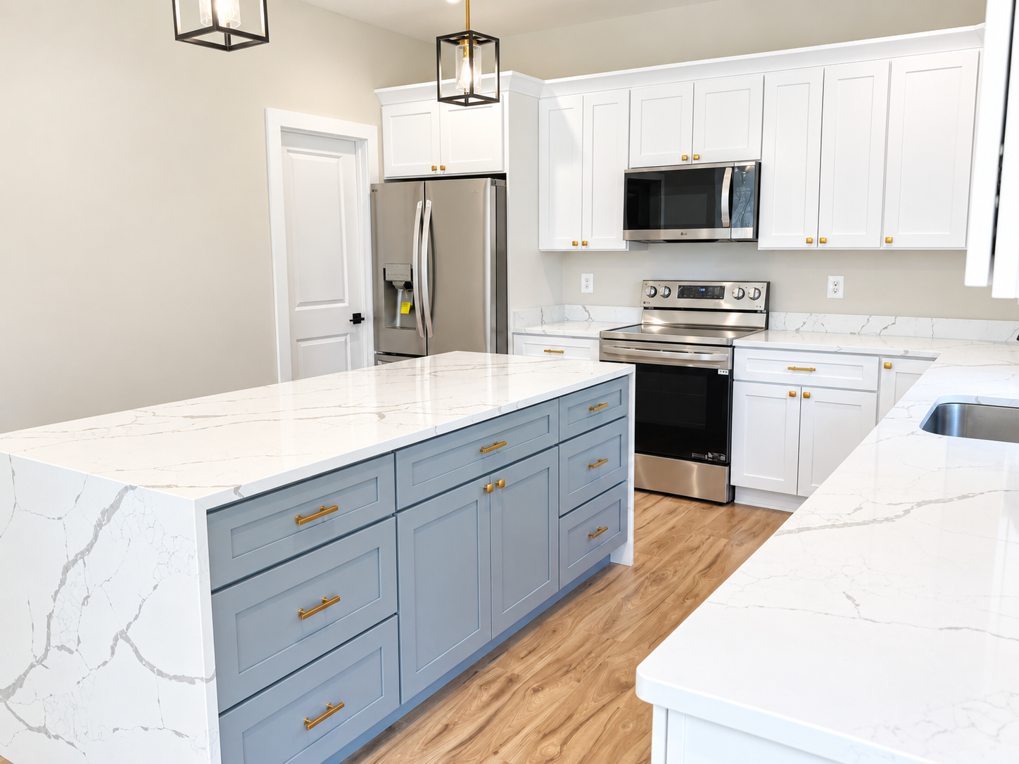 Kitchen with blue island, marble counters, and white cabinetry