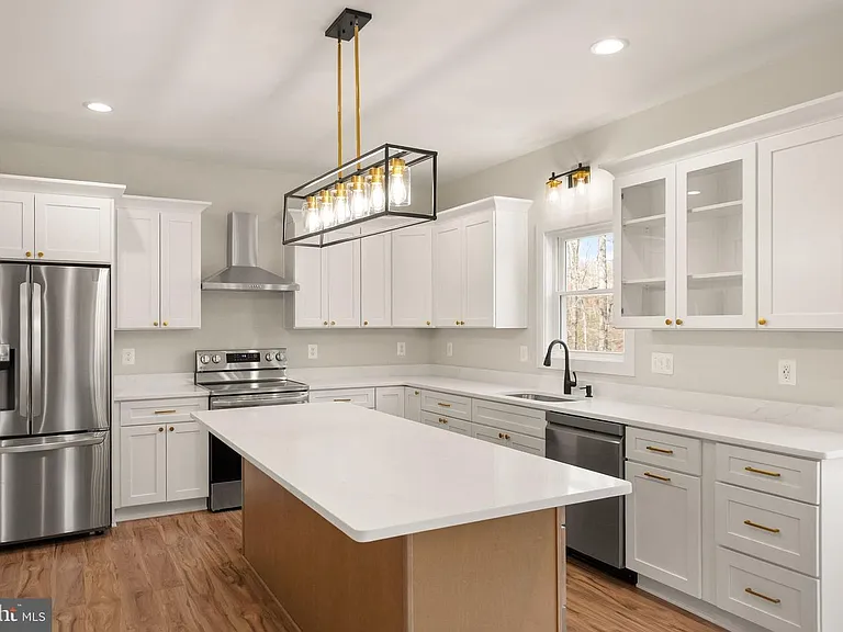 White kitchen with waterfall island and brass pendant